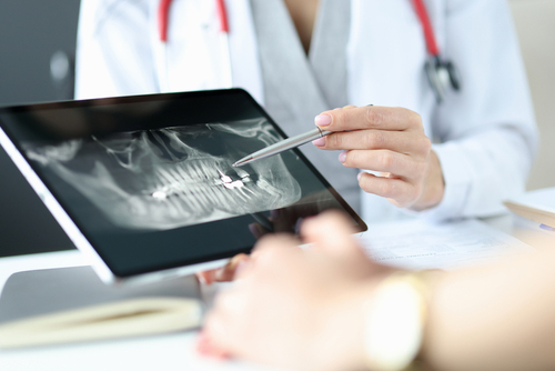 Dentist explaining dental imaging results to patient during examination - dental practice marketing