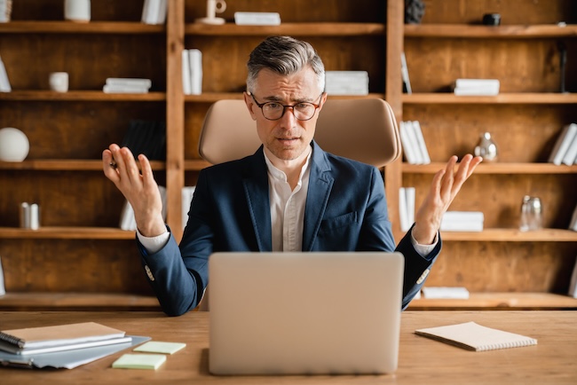 Frustrated attorney reviewing declining Google Ads metrics and wasted PPC budget on laptop in law office