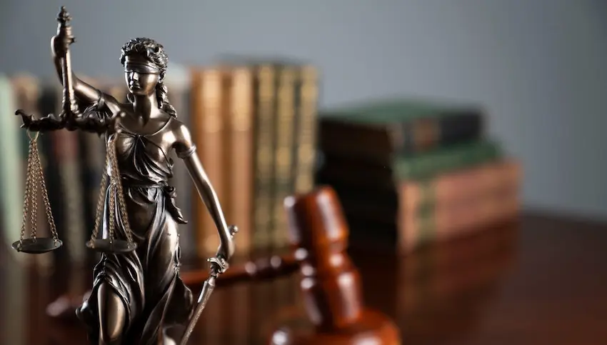 Bronze Lady Justice statue with scales and sword beside gavel and law books representing local SEO for legal services.