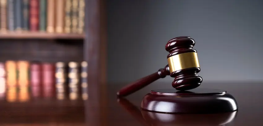 A wooden judge's gavel with a gold band is resting on a sound block in front of law books representing SEO for legal firms.