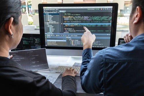 Two developers looking at code on monitors to represent healthcare website design services.